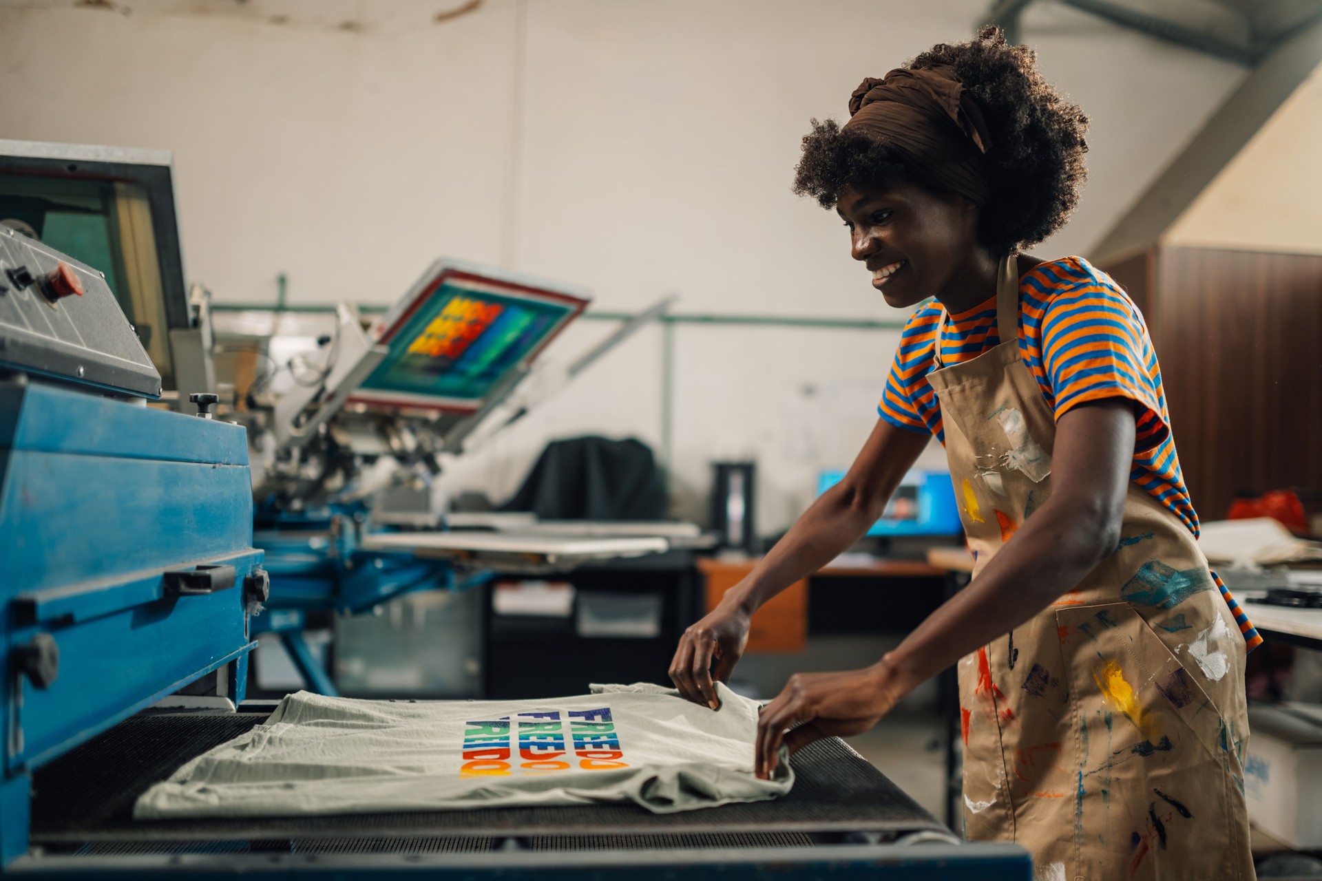 Happy interracial print shop worker putting product into a dryer.