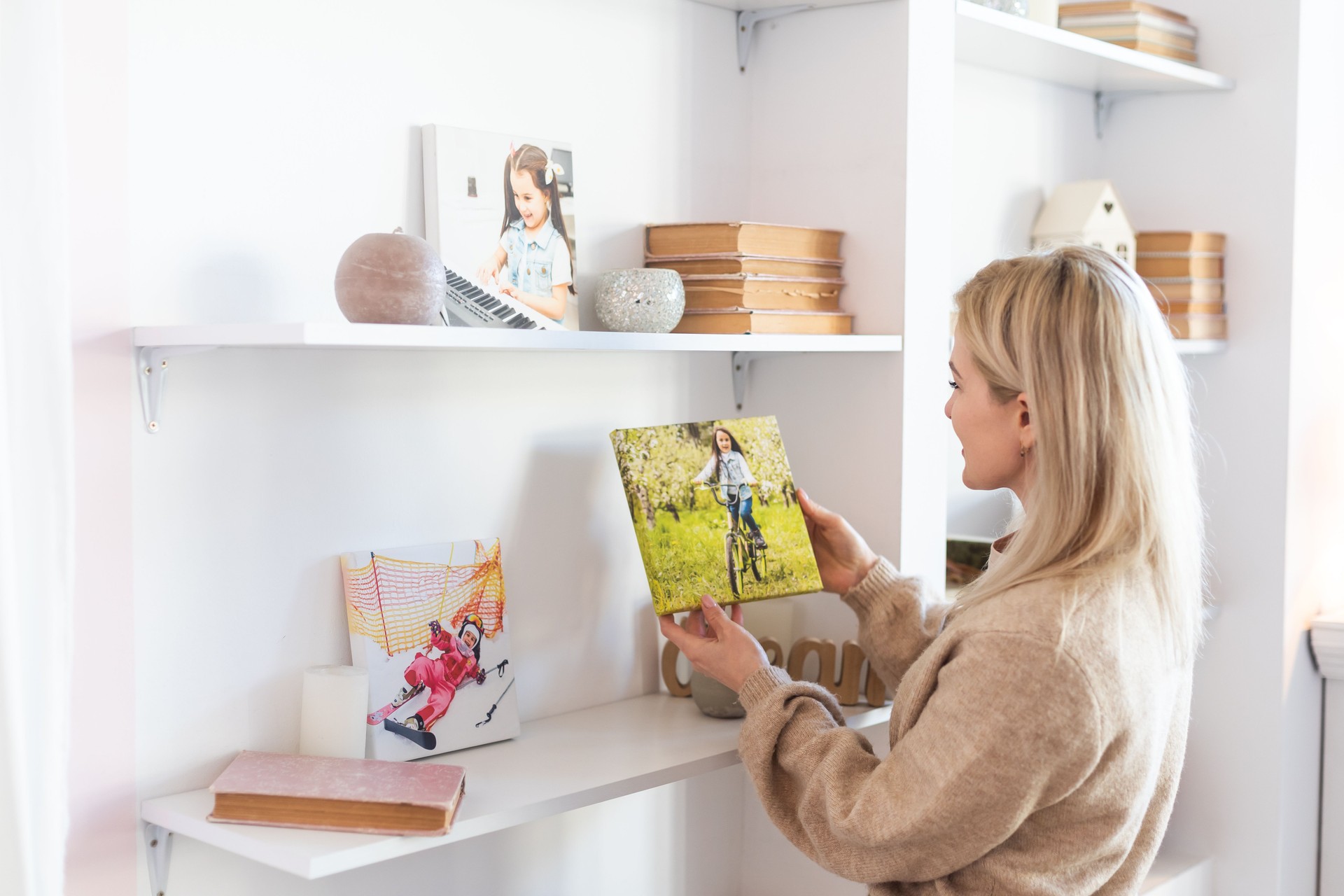 Young woman hanging a photo canvas painting on the wall